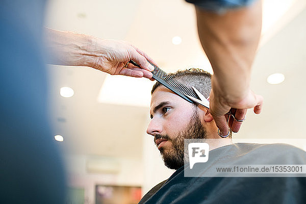 Hairdresser trimming customer's hair in barber shop