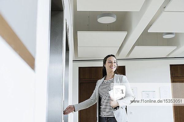 Geschäftsfrau mit digitaler Tablett-Drucktaste des Aufzugs