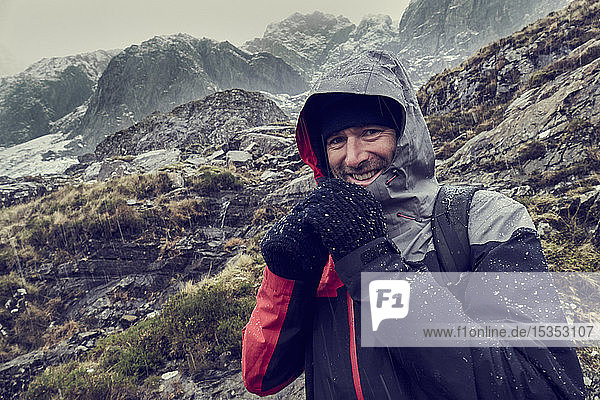 Männlicher Wanderer mit Kapuze in schneebedeckter Berglandschaft  Porträt  Llanberis  Gwynedd  Wales