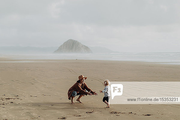 Mother and toddler playing with sand on beach  Morro Bay  California  United States