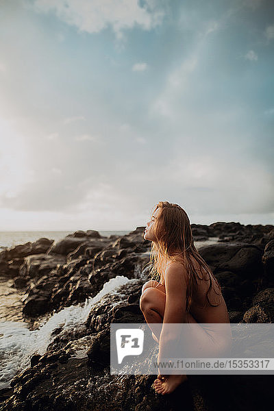Nackte Frau sitzt auf Felsen am Meer  Princeville  Hawaii  USA