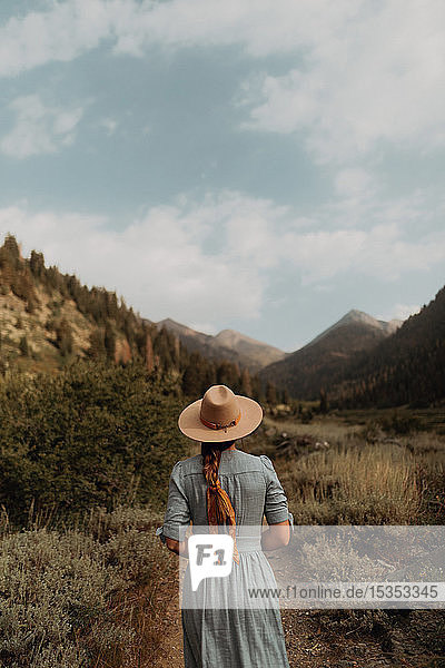 Junge Frau in Stetson und Maxi-Kleid beim Spaziergang auf dem Feldweg im ländlichen Tal  Rückansicht  Mineral King  Kalifornien  USA