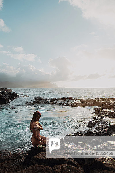 Naked woman sitting on rocks by sea pool  Princeville  Hawaii  US