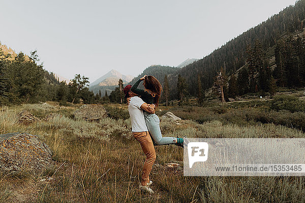 Young man lifting up his girlfriend in rural valley  Mineral King  California  USA
