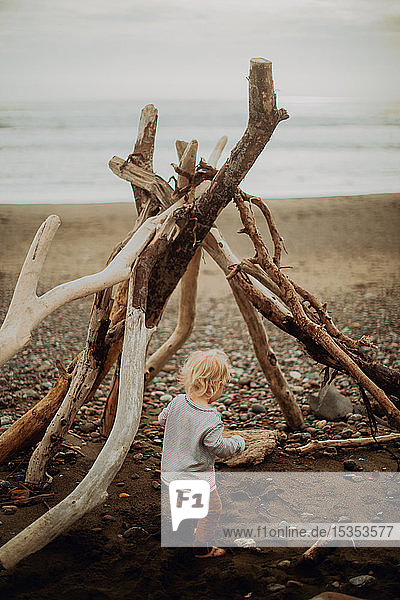 Kleinkind spielt neben Wigwam am Strand