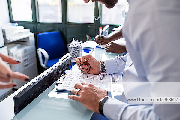 Patienten füllen Formulare mit Hilfe der Krankenschwester am Krankenhausempfang aus