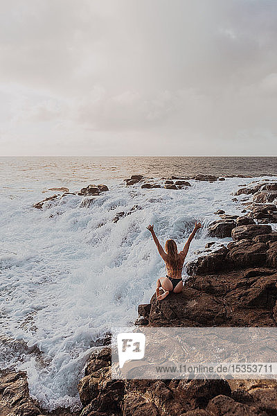 Frau sitzt auf Felsen am Meer  Princeville  Hawaii  USA