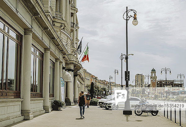 Fußgänger gehen an historischer Architektur entlang einer Straße vorbei; Italien