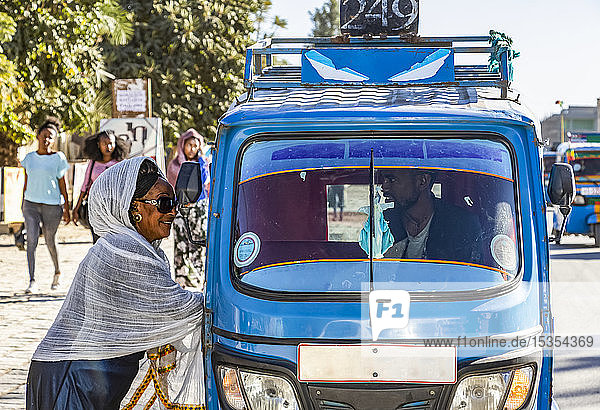 Woman by an auto rickshaw talking to the driver through the window; Wukro  Tigray Region  Ethiopia