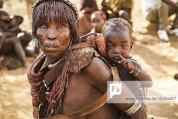 Hamer woman carrying a baby at a bull jumping ceremony  which initiates a boy into manhood  in the village of Asile  Omo Valley; Southern Nations Nationalities and Peoples' Region  Ethiopia