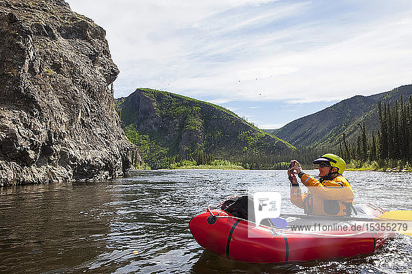 Woman photographing from her Packrafting on the Charley River in summertime  Yukonâ€“Charley Rivers National Preserve; Alaska  United States of America