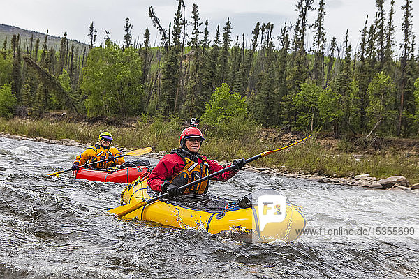 Zwei Packrafterinnen  die im Sommer einen Nebenfluss des Charley River befahren  Yukonâ€ Charley Rivers National Preserve; Alaska  Vereinigte Staaten von Amerika