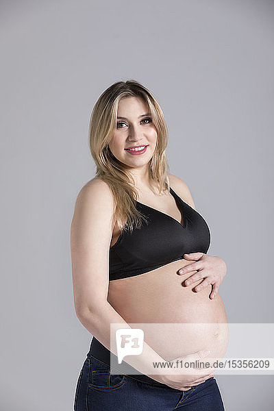 Eine junge schwangere Frau hält ihren Bauch in einem Studio und posiert für die Kamera; Edmonton  Alberta  Kanada