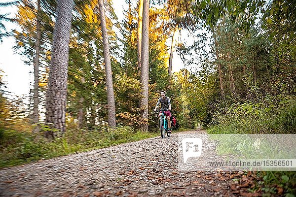 Young man cycling in the autumn forest  Perlacher Forst  Munich  Upper Bavaria  Bavaria  Germany  Europe