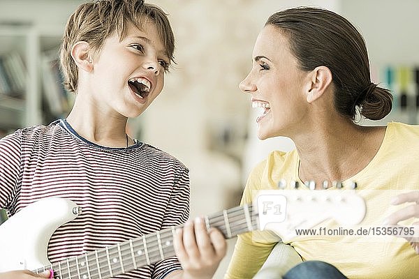 Mutter und Sohn musizieren zusammen  beide singen und Sohn spielt E-Gitarre  Nahaufnahme  lachend  Deutschland  Europa