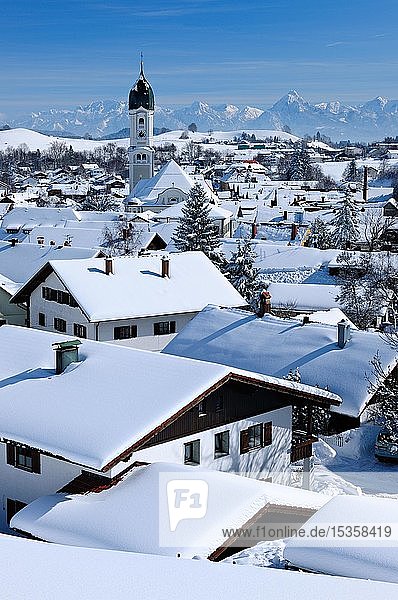 Blick auf schneebedeckte Dächer im Winter mit St. Andreas Kirche  Allgäuer Alpen im Hintergrund  Nesselwang  Allgäu  Bayern  Deutschland  Europa