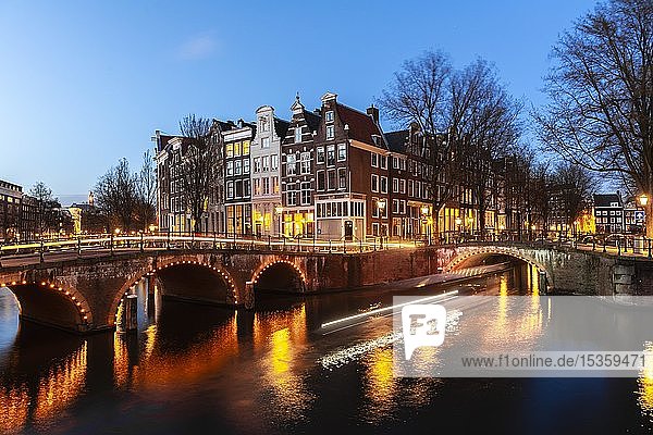 Abendstimmung  Lichtspuren  Bootsfahrten durch Gracht mit Brücke  Keizersgracht und Leidsegracht  Gracht mit historischen Häusern  Amsterdam  Nordholland  Niederlande
