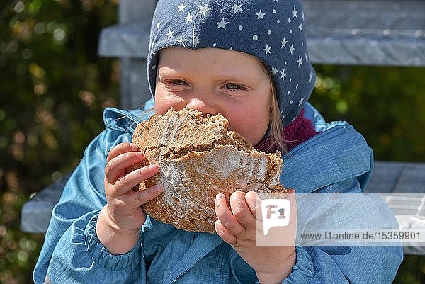 Kleines Mädchen beißt herzhaft in ein Schwarzbrot Chile Südamerika