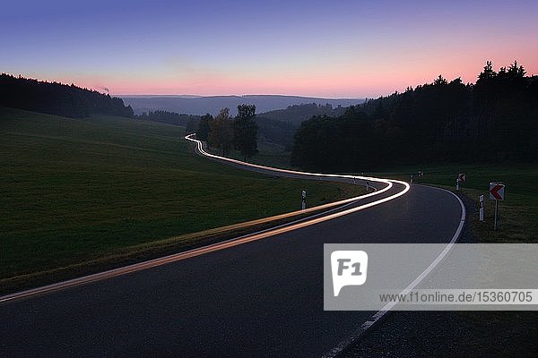 Autofahrt auf kurvenreicher Landstraße am Abend  weiße Lichtspuren  bei Bad Lobenstein  Thüringen  Deutschland  Europa