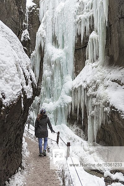 Junge Frau in der vereisten Partnachklamm mit Eiszapfen und Schnee im Winter  bei Garmisch-Partenkirchen  Oberbayern  Bayern  Deutschland  Europa