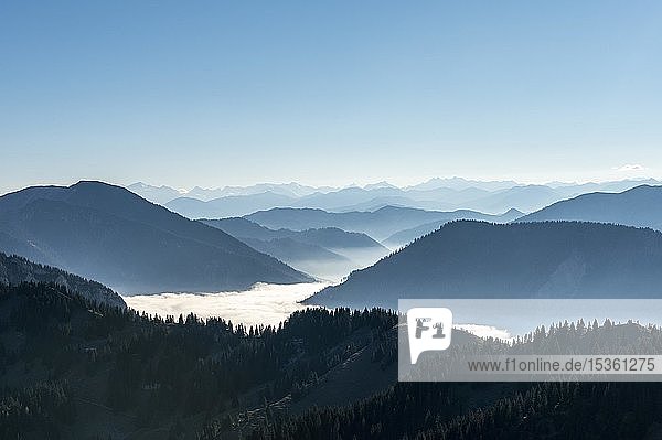Bergketten hintereinander im Gegenlicht  Blick auf Alpenpanorama vom Gipfel des Breitensteins  Hochnebel über dem Tal  Fischbachau  Bayern  Deutschland  Europa