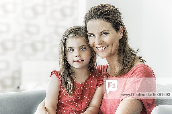 Mutter und Tochter sitzen zusammen auf der Couch und schauen in die Kamera  lächeln  Deutschland  Europa