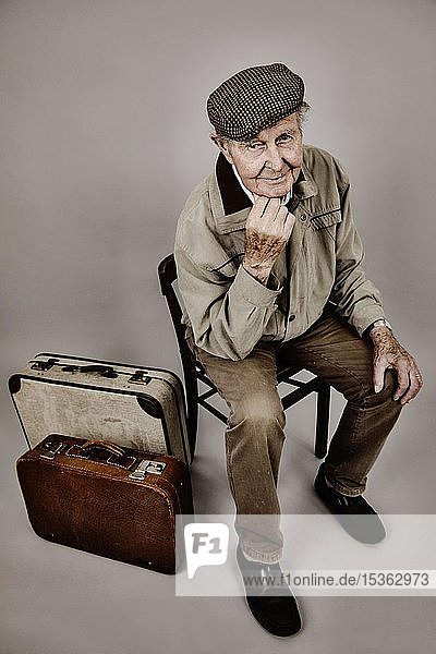 Senior sitzt mit altem Koffer auf einem Stuhl  Symbolbild Abschied  Sehnsucht  Studioaufnahme  Deutschland  Europa