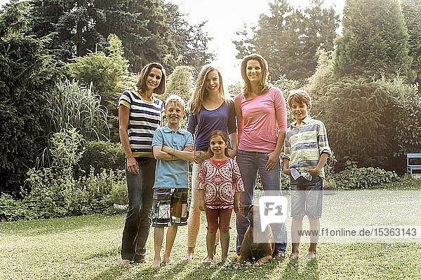 Zwei Mütter mit ihren vier Kindern und Hund im Garten  Gruppenbold  Deutschland  Europa