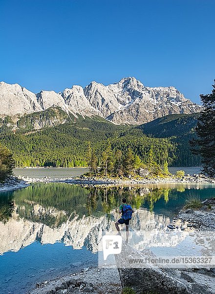 Wanderer auf Felsen stehend  Blick in die Ferne  Zugspitze und Wettersteingebirge mit Spiegelung im Eibsee  bei Grainau  Oberbayern  Bayern  Deutschland  Europa