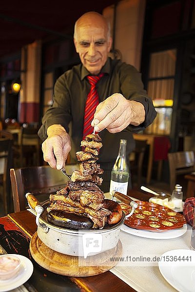 Older man serving traditional brasero or grilled meat  Montevideo  Uruguay  South America