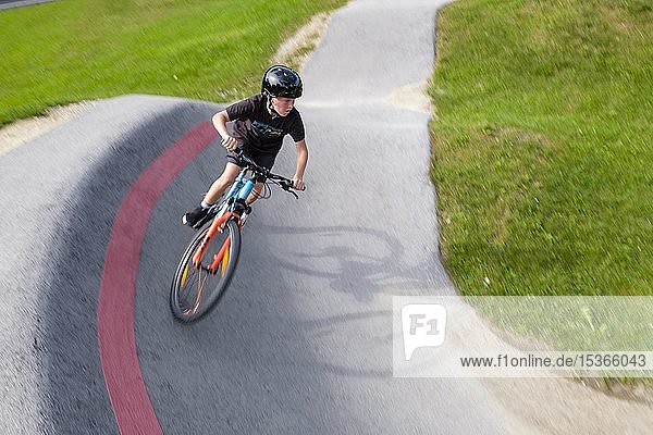 Child  boy  11 years old  riding a mountain bike through a steep curve in a pump track  mountain bike trail  Viehhausen  Salzburg  Austria  Europe