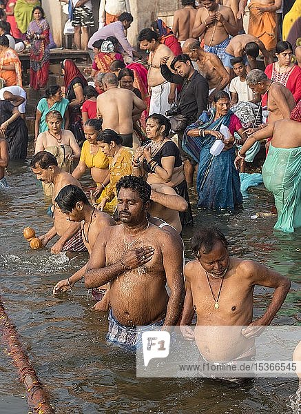 Hinduistische Gläubige nehmen ein rituelles Bad und verrichten Puja-Gebete an Ghats im Fluss Ganges  Varanasi  Uttar Pradesh  Indien  Asien