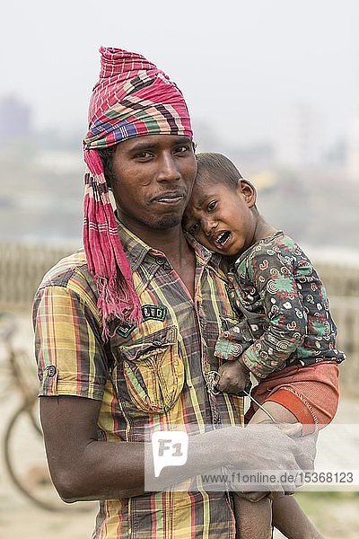 Man with crying toddler on his arm  Dhaka  Bangladesh  Asia