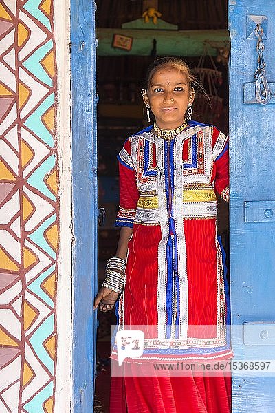 Junges Mädchen in traditioneller farbenfroher Kleidung steht in einer Tür  Khavda  Bezirk Kutch  Great Rann of Kutch  Gujarat  Indien  Asien
