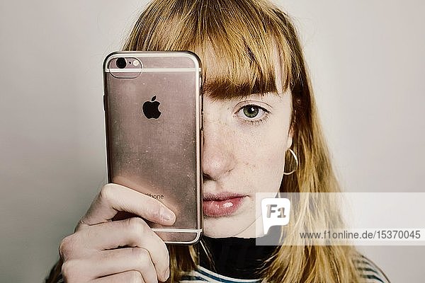 Mädchen mit einem Apple iPhone  Apple-Logo als Auge  Studioaufnahme  Deutschland  Europa