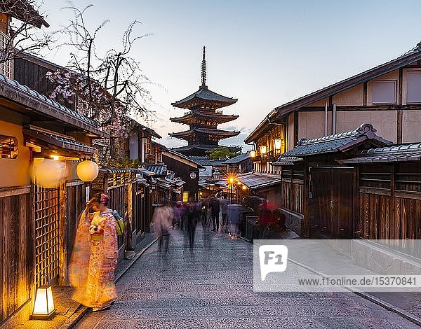 Woman in kimono and pedestrian in an alleyway  Yasaka dori historical alleyway in the old town with traditional Japanese houses  rear five-storey Yasaka pagoda of the Buddhist H?kanji Temple  evening mood  Kyoto  Japan  Asia