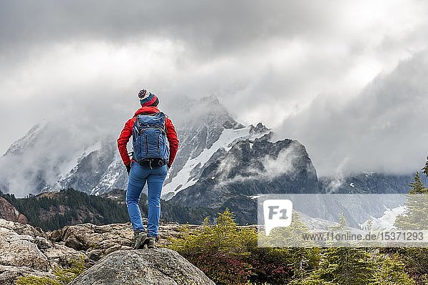 Female hiker looks into the distance  mountain landscape in autumn  glacier at the back Mt. Shuksan with snow in clouds  Mt. Baker-Snoqualmie National Forest  Washington  USA  North America