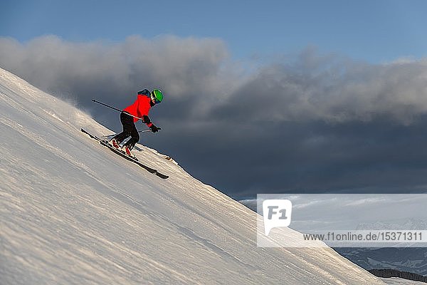 Female skier skiing steep downhill  black piste  behind mountains  Brixen im Thale  Tyrol  Austria  Europe