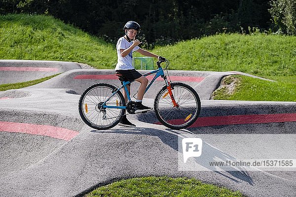 Child  boy  11 years old in a casual pose on a mountain bike in a pump track  mountain bike trail  Viehhausen  Salzburg  Austria  Europe