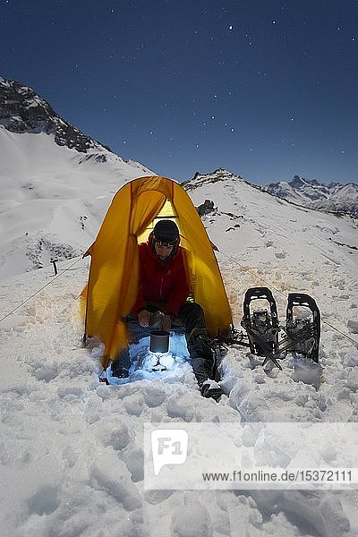 Schneeschuhwanderer beim Schmelzen von Schnee für Trinkwasser im Schnee auf dem Mädelejoch  Nachtaufnahme  nahe Kemptner Hütte  Allgäuer Alpen  Tirol  Österreich  Europa
