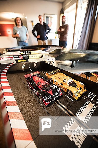 Men playing in the living room with a large Carrera train  model highway  Cologne  North Rhine-Westphalia  Germany  Europe