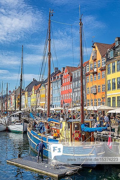 Elderly man washing his boat  coloured houses and sailing boats on Nyhavn canal  Copenhagen  Denmark  Europe