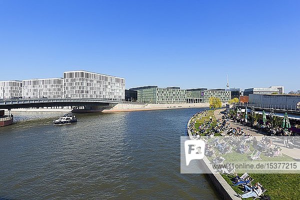 Ludwig Erhard Ufer at the river Spree with deckchairs  on the left the Hugo Preuß Bridge with PricewaterhouseCoopers and the Federal Ministry of Education and Research  Berlin  Germany  Europe