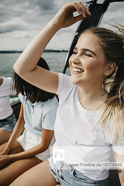Glückliche junge Frau mit Freunden bei einer Bootsfahrt auf einem See