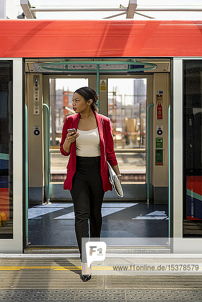 Businesswoman with cell phone getting out off the train  London  UK