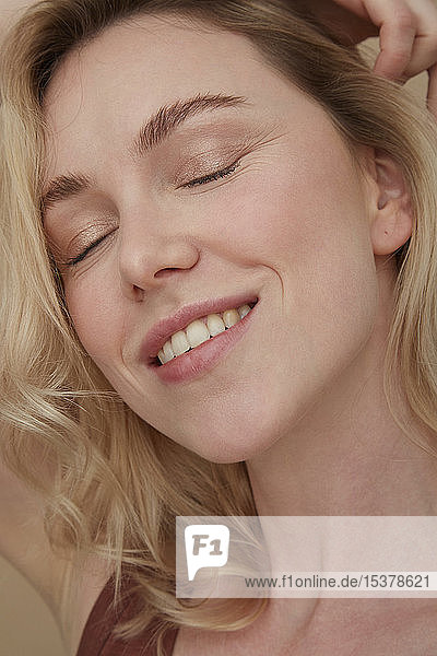 Portrait of happy blond woman wearing with eyes closed