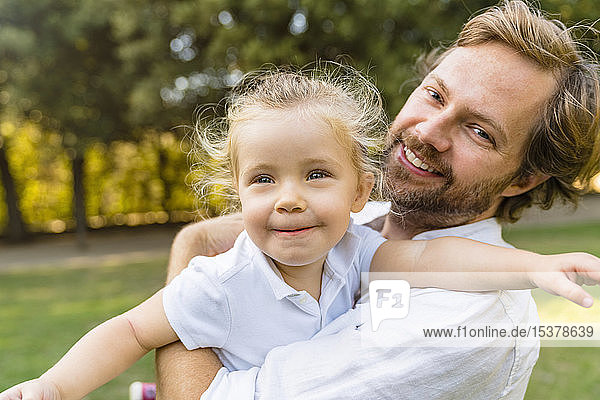 Glücklicher Vater spielt mit kleiner Tochter in einem Park