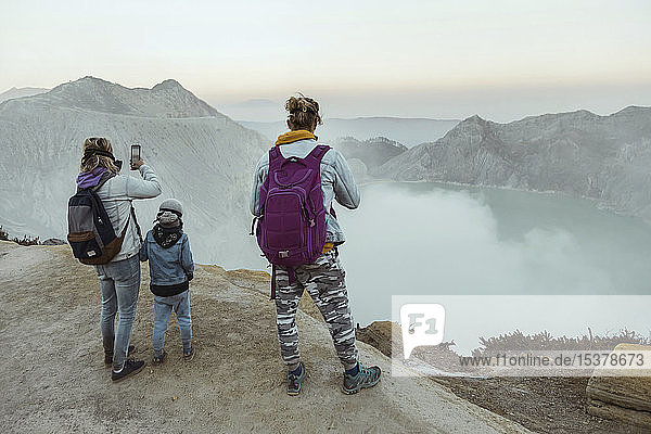 Family with respirator masks standing at the edge of volcano Ijen Java Indonesia