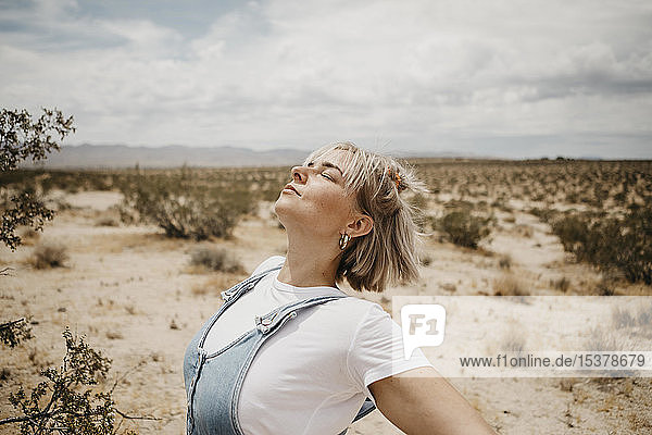 Junge Frau in Wüstenlandschaft mit geschlossenen Augen  Joshua-Tree-Nationalpark  Kalifornien  USA