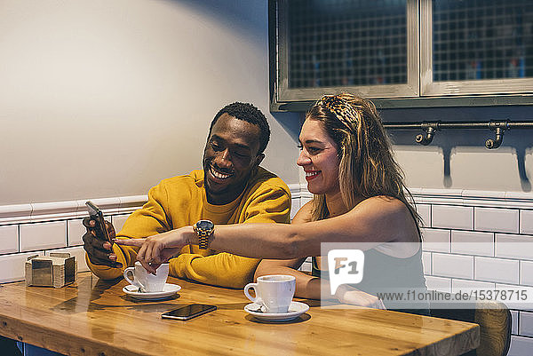 Porträt eines lächelnden Paares in einem Café mit Smartphone